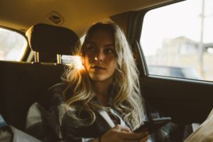 Young woman in backseat of car using phone